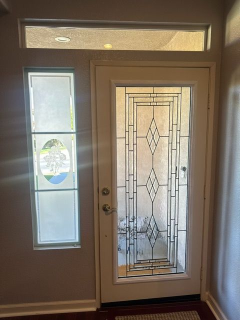 White front door with stained glass design and frosted sidelight.