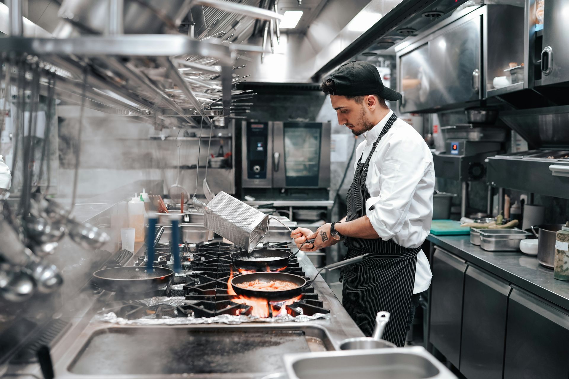 A chef is cooking food in a commercial kitchen.