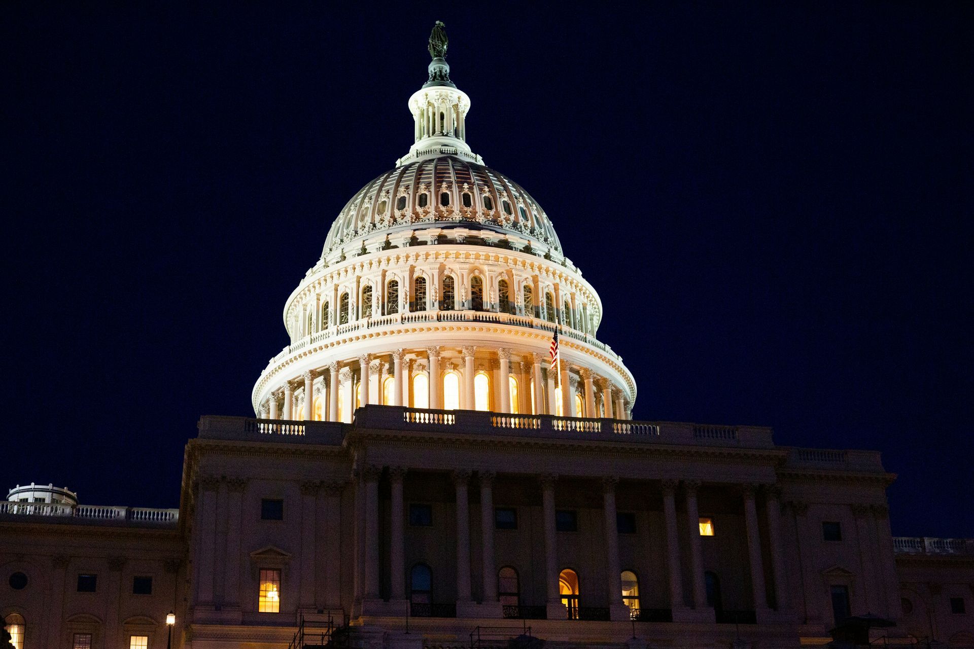 The dome of the capitol building is lit up at night