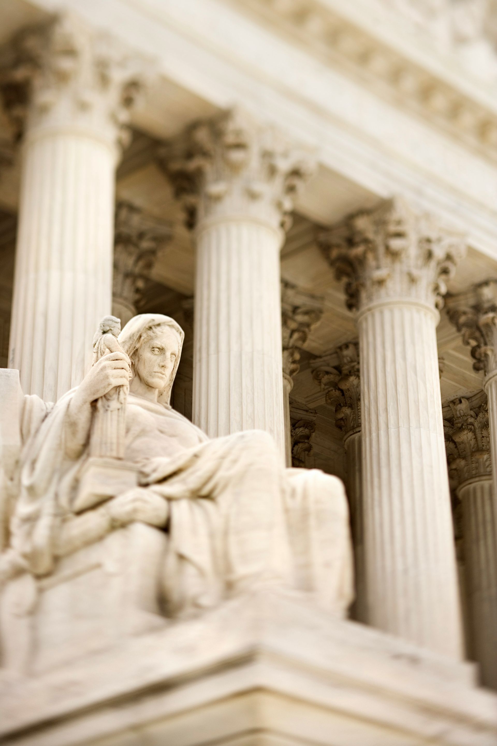 A statue of a woman holding a microphone in front of a building with columns.