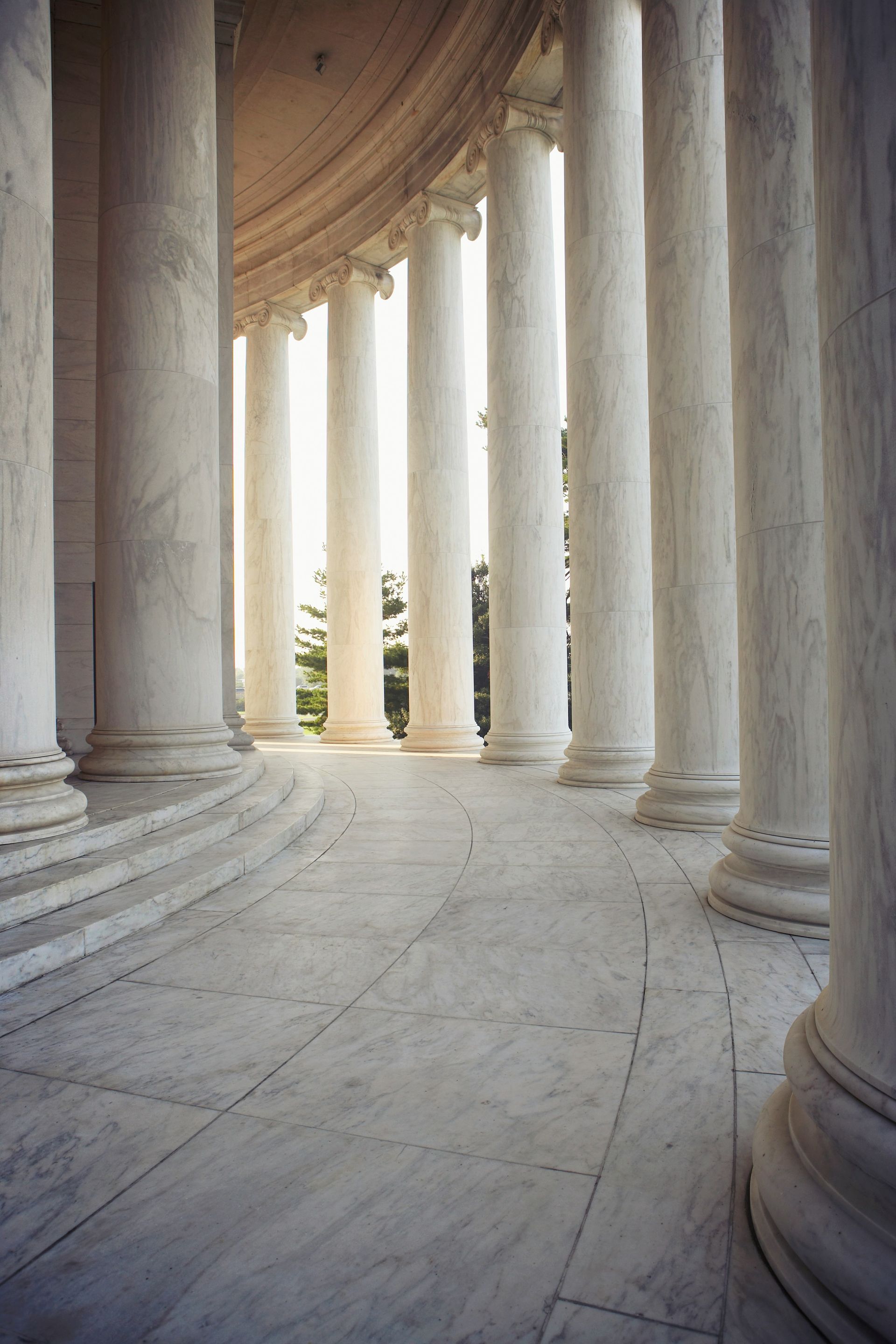 A row of columns in a building with trees in the background