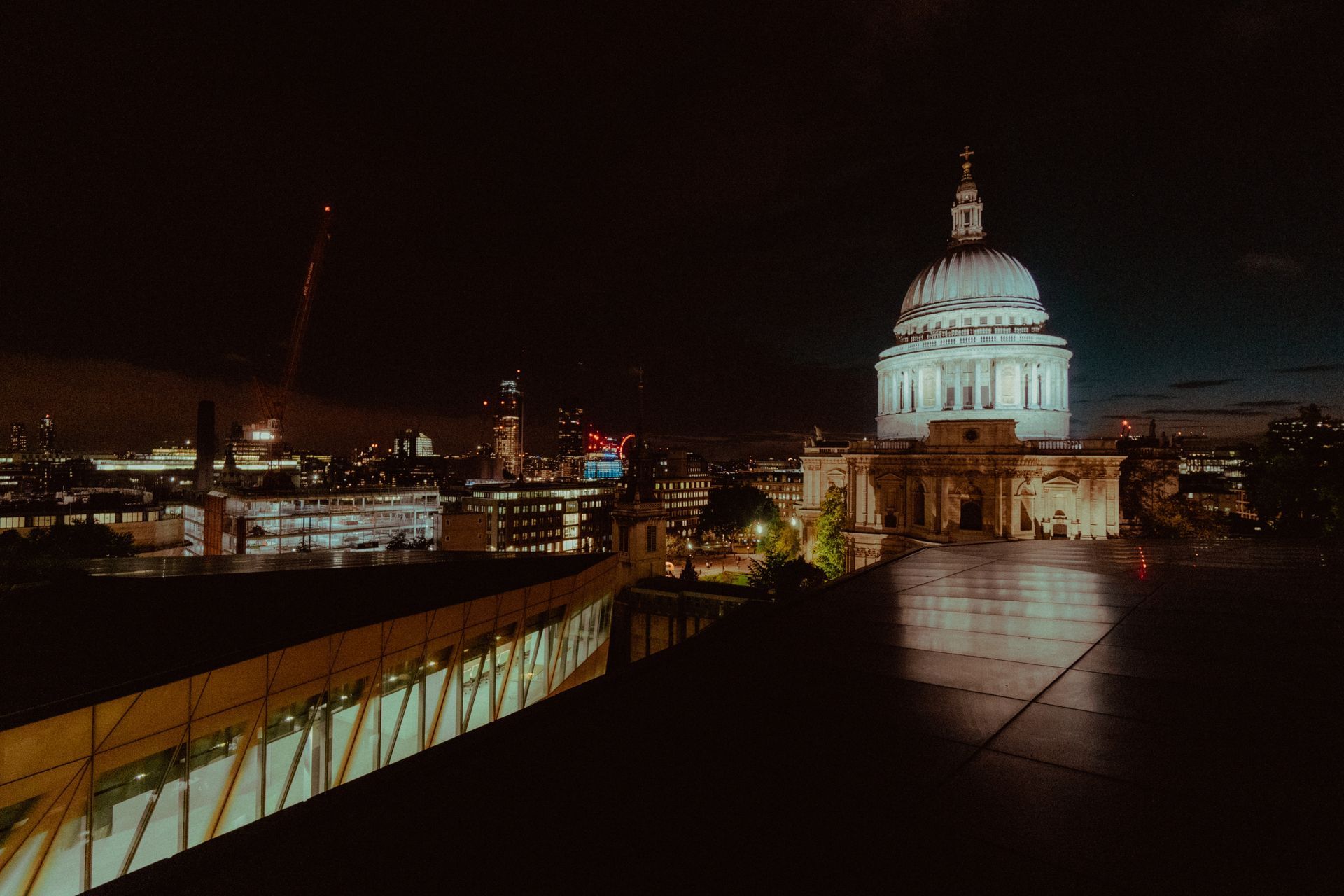 A large dome is lit up at night in a city.