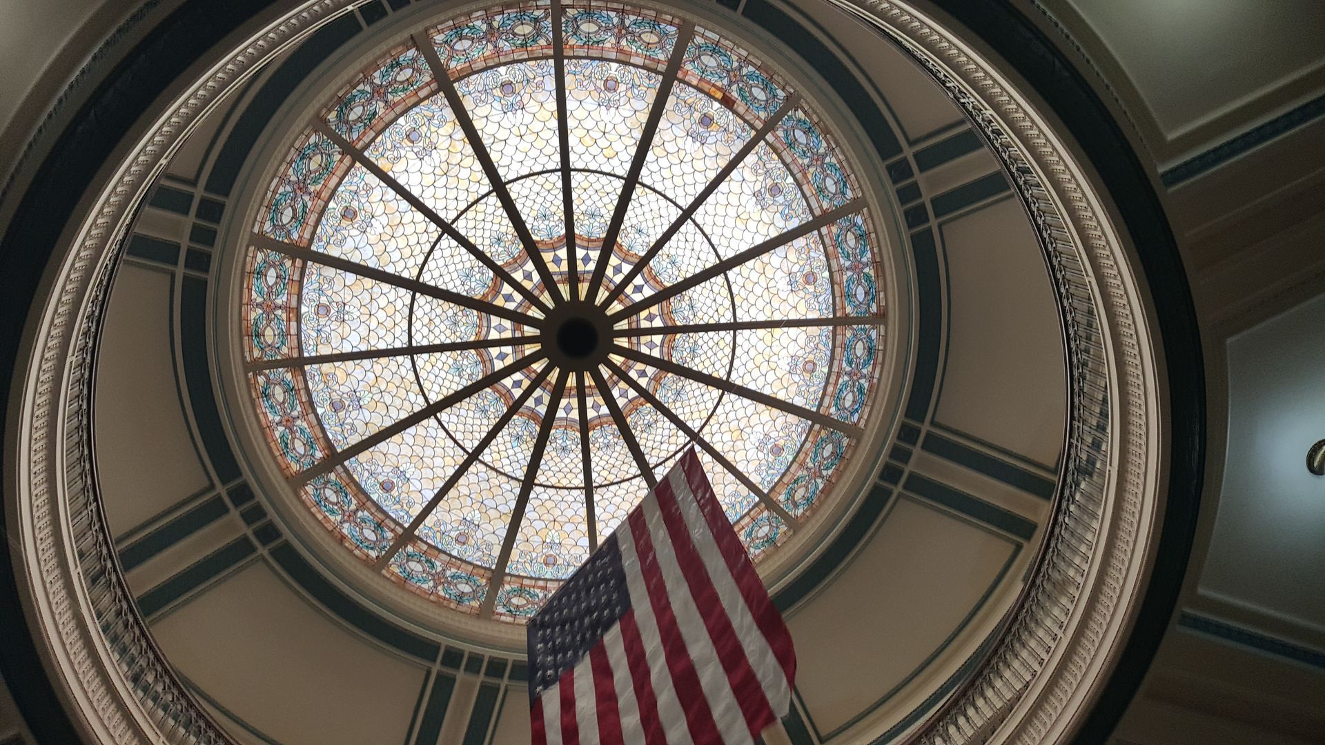 The american flag is flying in the dome of a building.