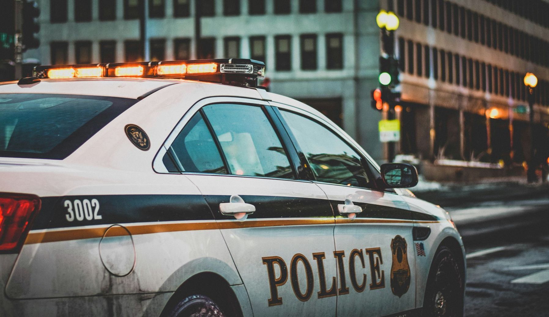 A police car is parked on the side of the road in front of a building.