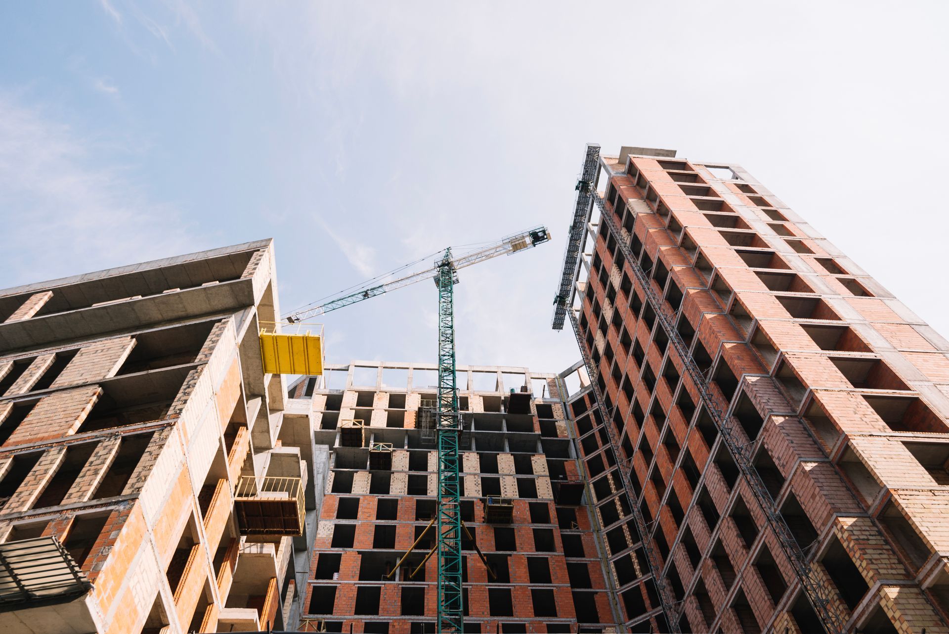 A tall building is being built with a crane in the foreground.