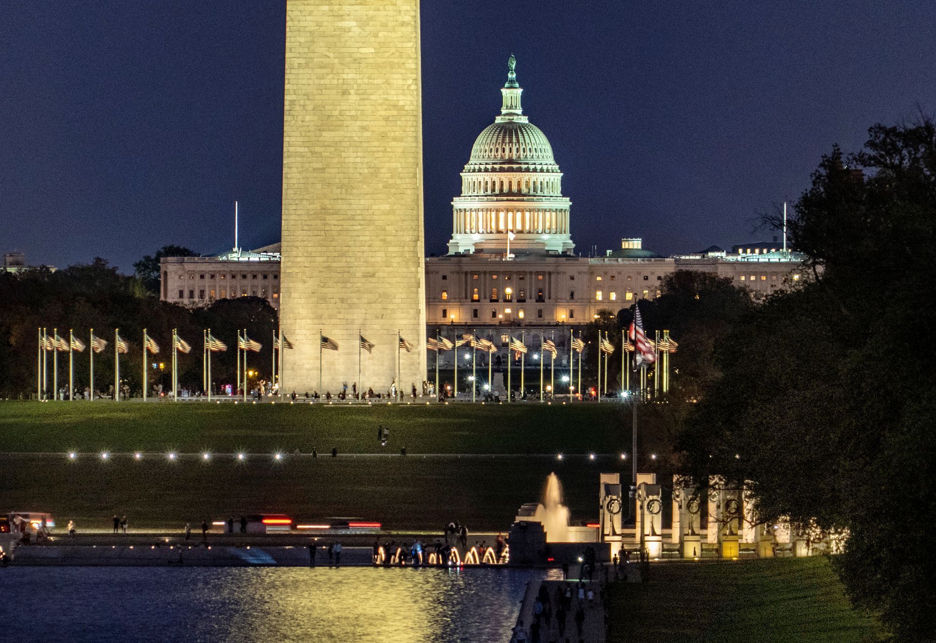 The washington monument and the capitol building are lit up at night