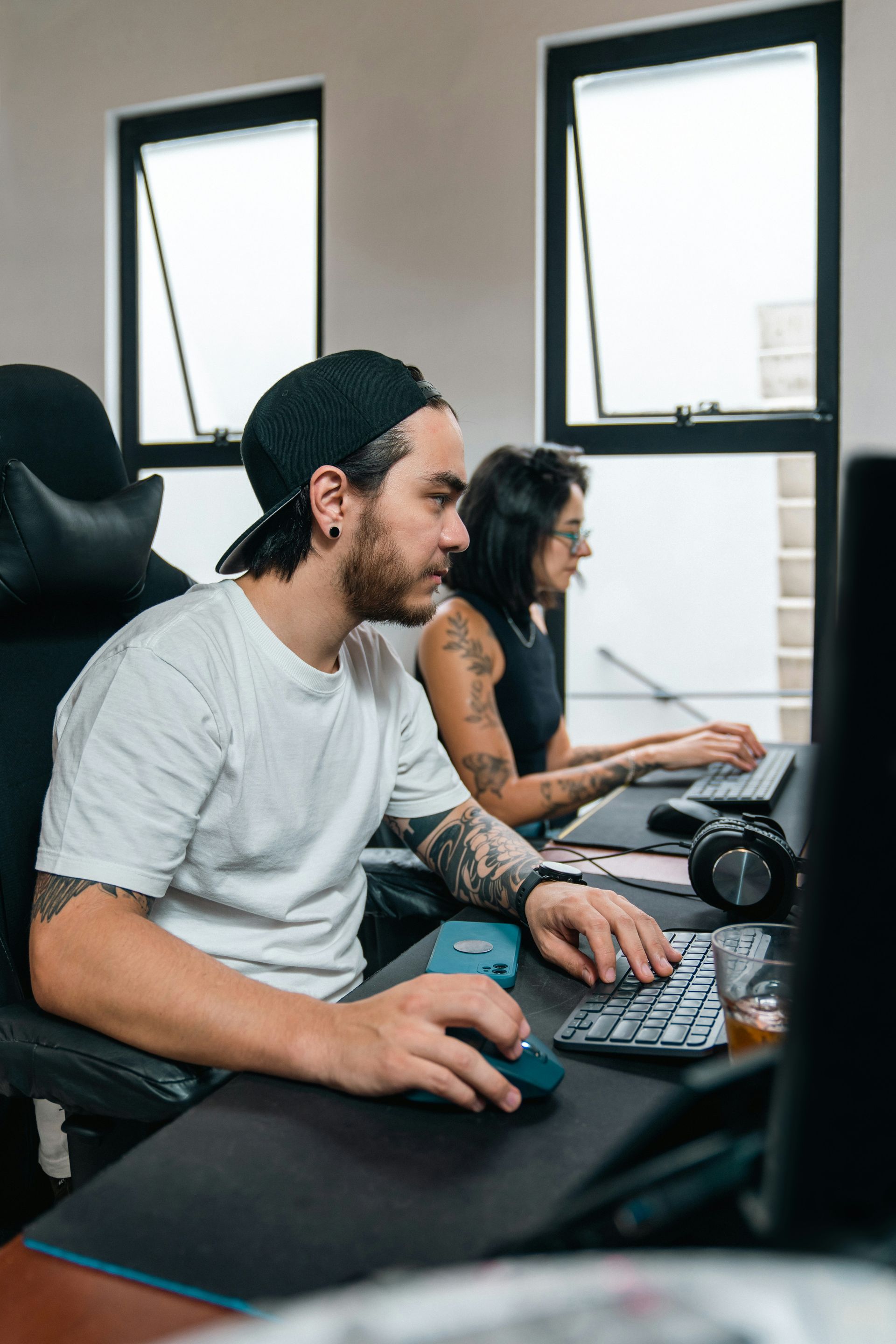 A man and a woman are sitting at a desk working on a computer.