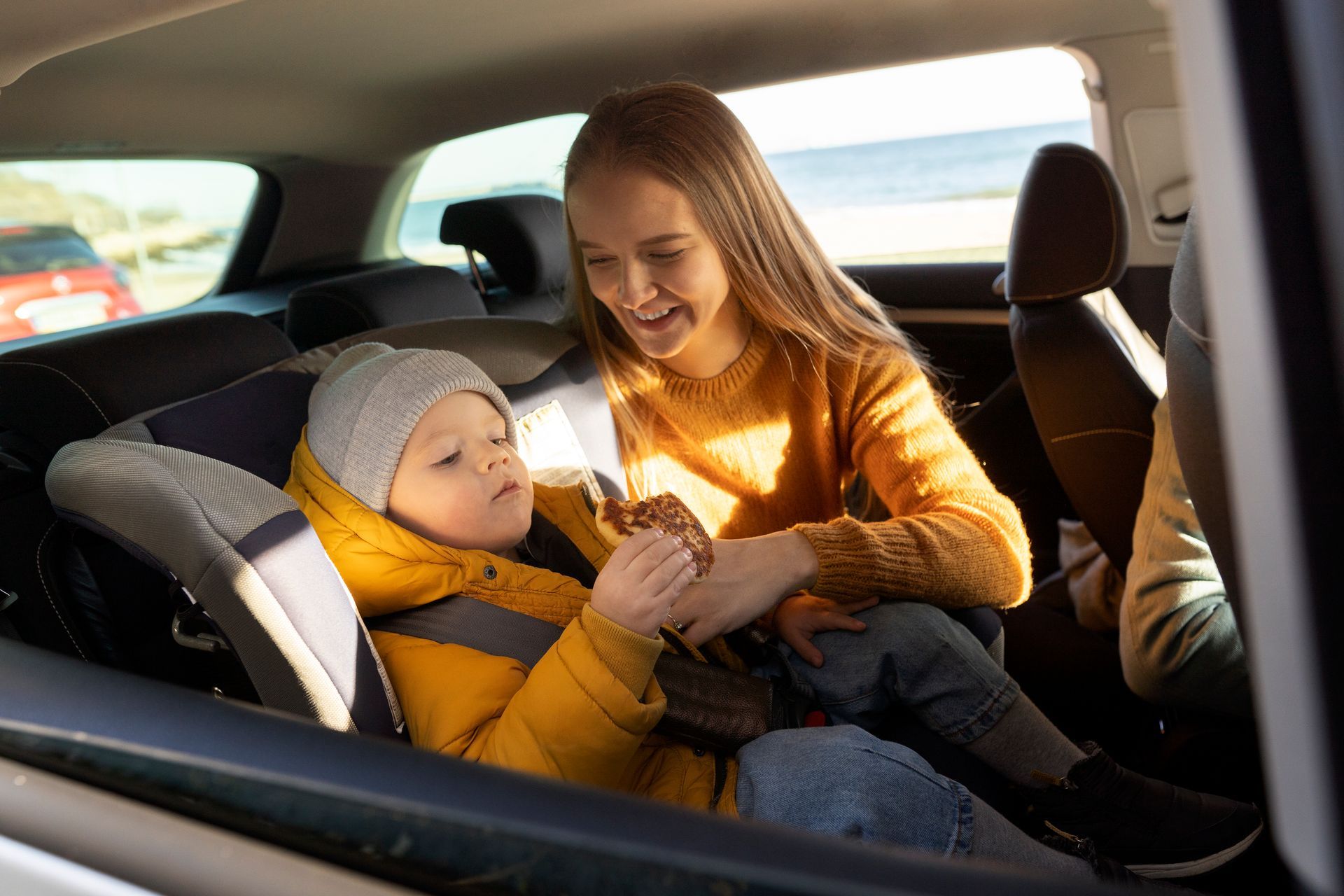 A woman is putting a child in a car seat.