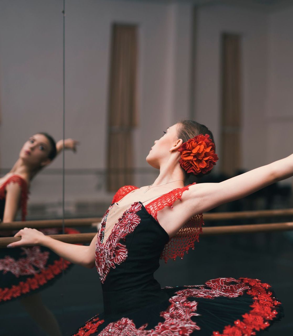 A ballerina is dancing in front of a mirror in a dance studio.