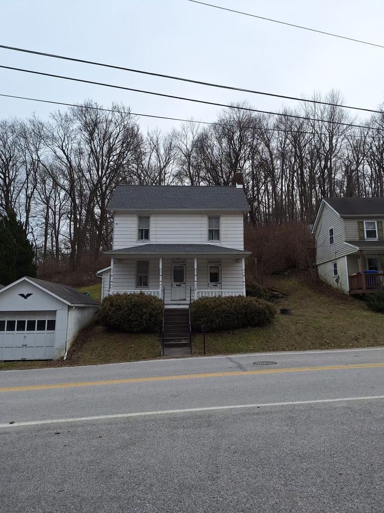 A white house sits on a hill next to a road