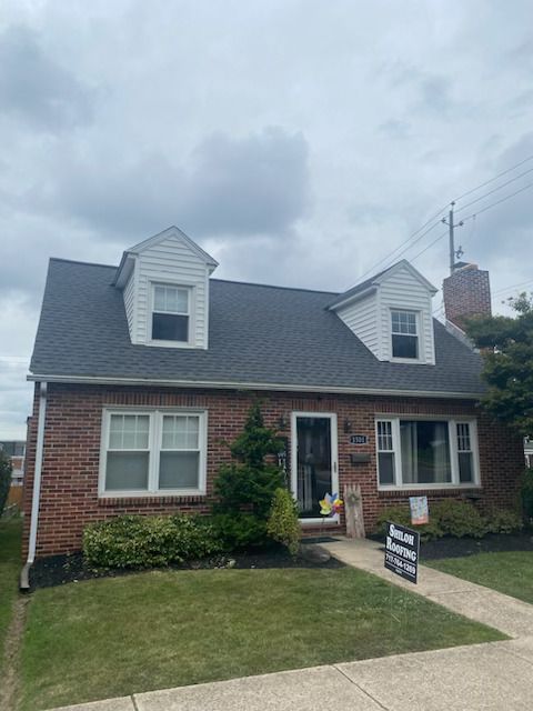 A brick house with a gray roof and white trim is for sale.