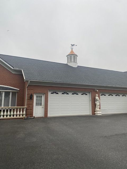 A house with three garage doors and a weather vane on top