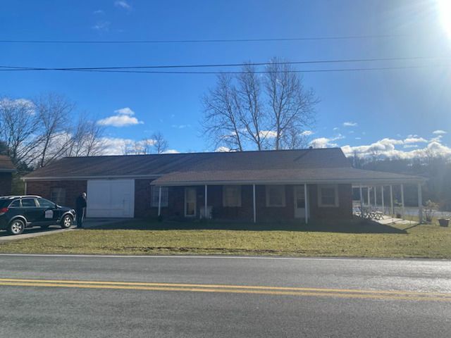 A house with a car parked in front of it on a sunny day.