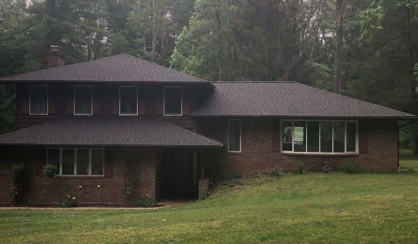 A large brick house with a large lawn in front of it.