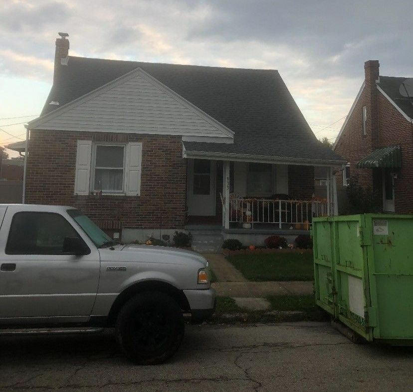 A white truck is parked in front of a brick house