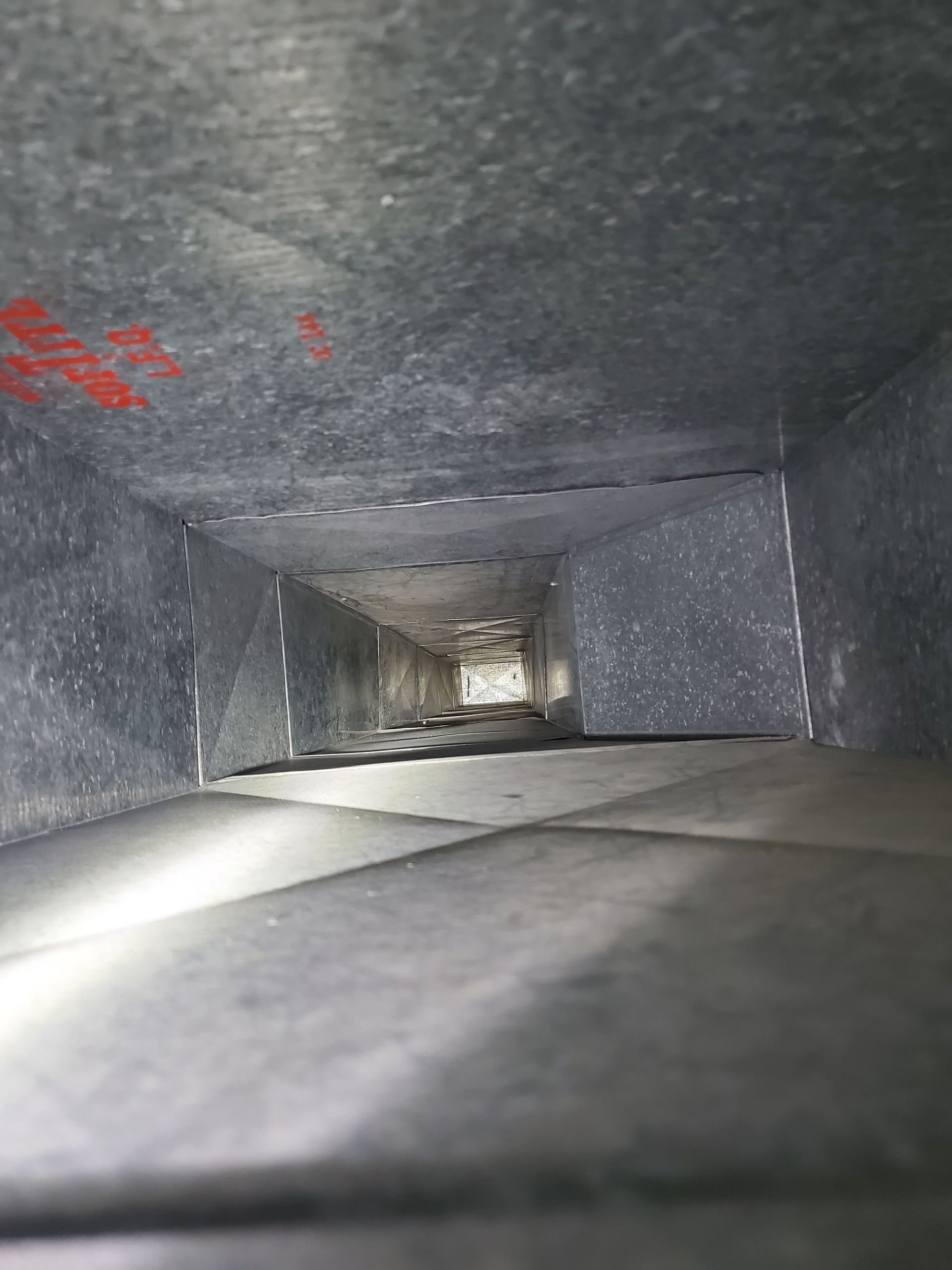Inside of a rectangular air duct, viewed from an angle. Duct is metal, with some rust spots. Inside of a rectangular air duct, viewed from an angle. Duct is metal, with some rust spots.