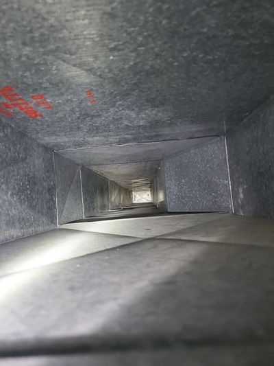 Inside of a rectangular air duct, viewed from an angle. Duct is metal, with some rust spots. Inside of a rectangular air duct, viewed from an angle. Duct is metal, with some rust spots.