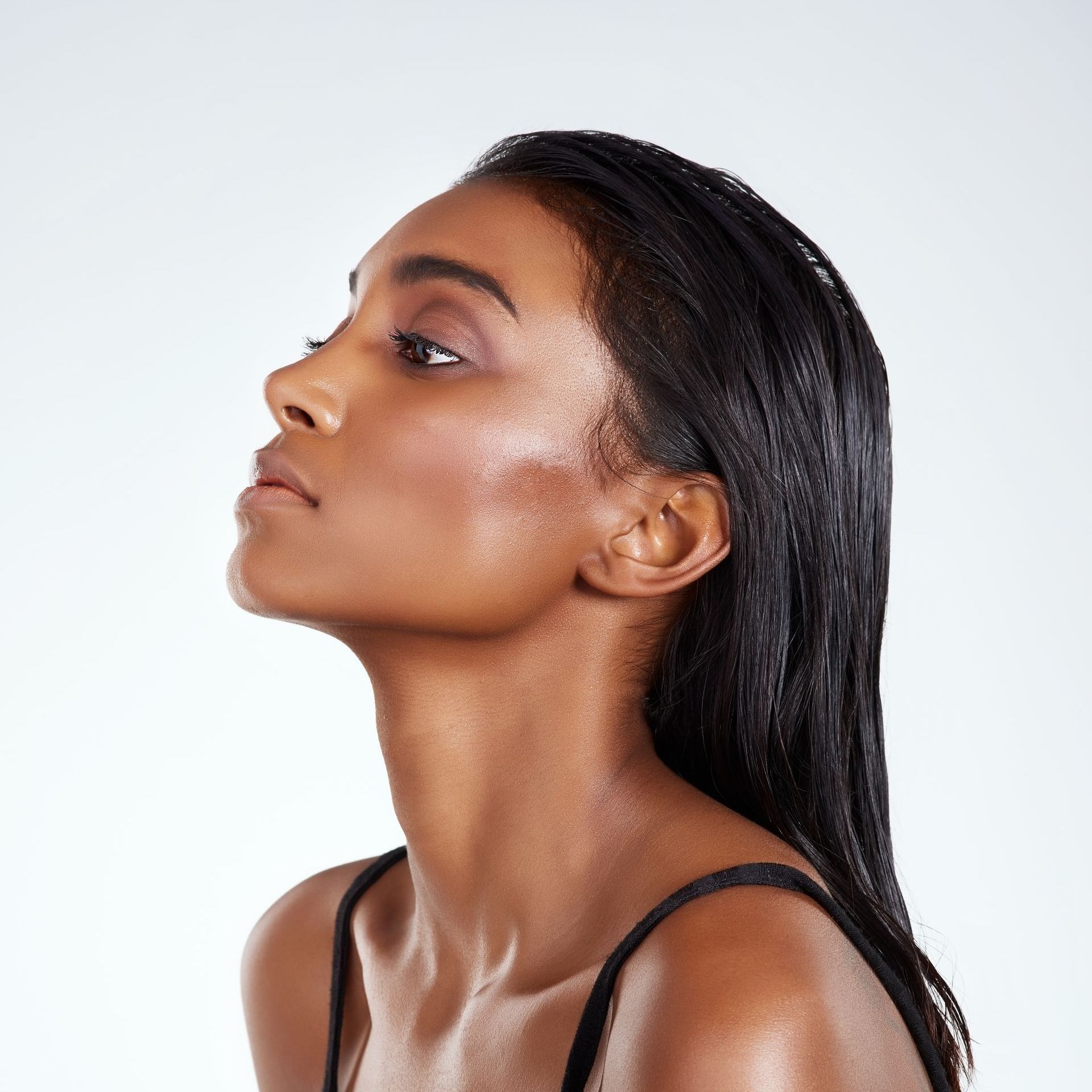 A close up of a woman 's face with wet hair against a white background.