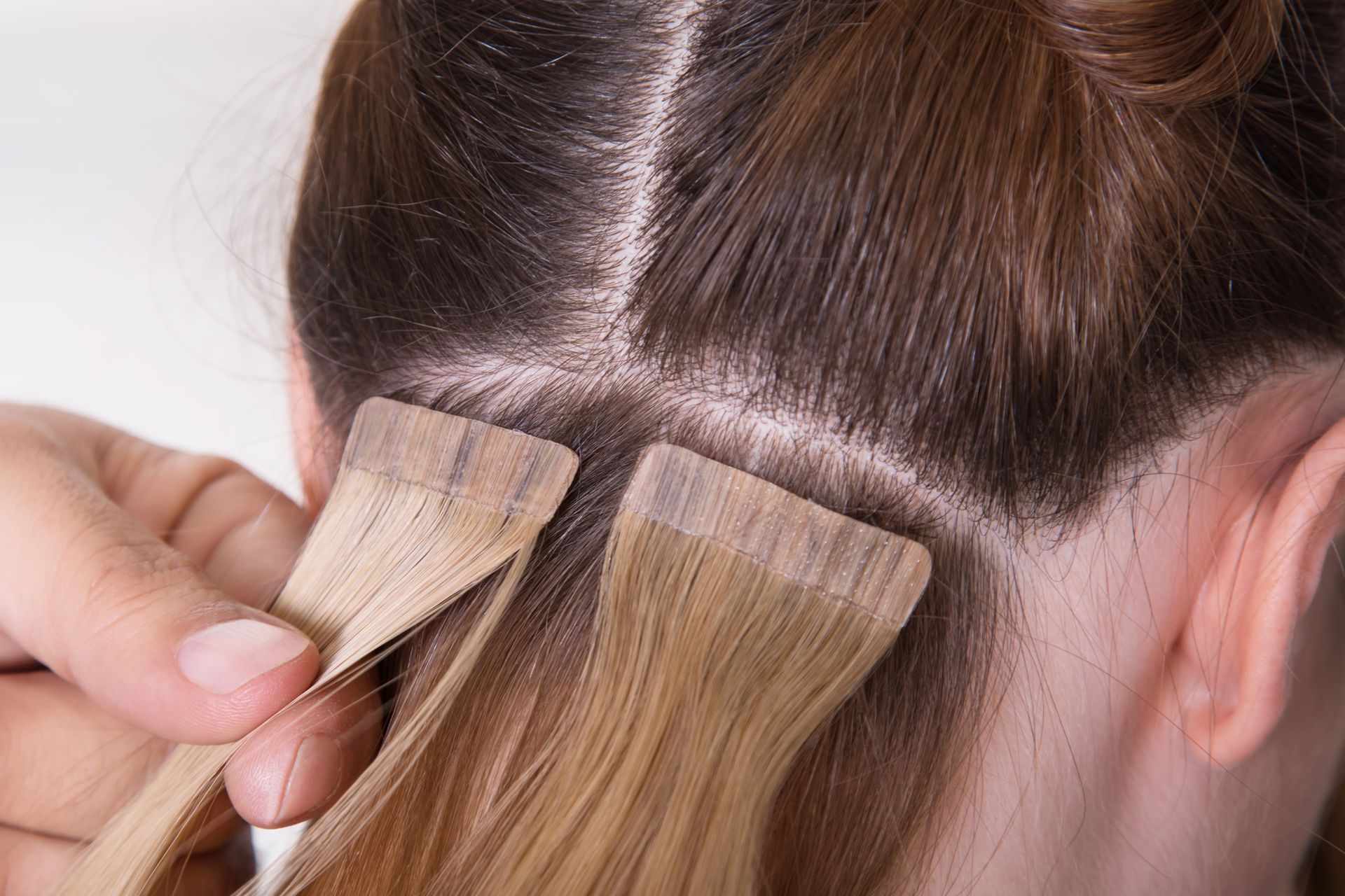 A woman is getting hair extensions in her hair.