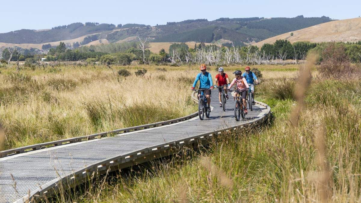 A group of people are riding bikes on a wooden bridge.