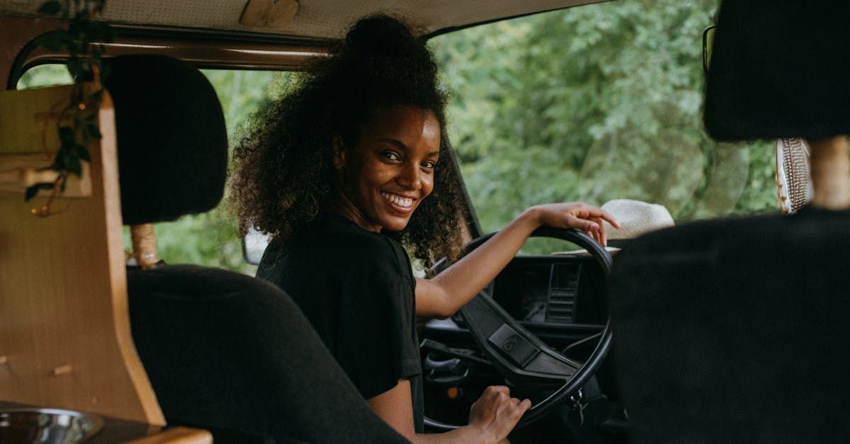 A woman is sitting in the driver 's seat of a car and smiling.