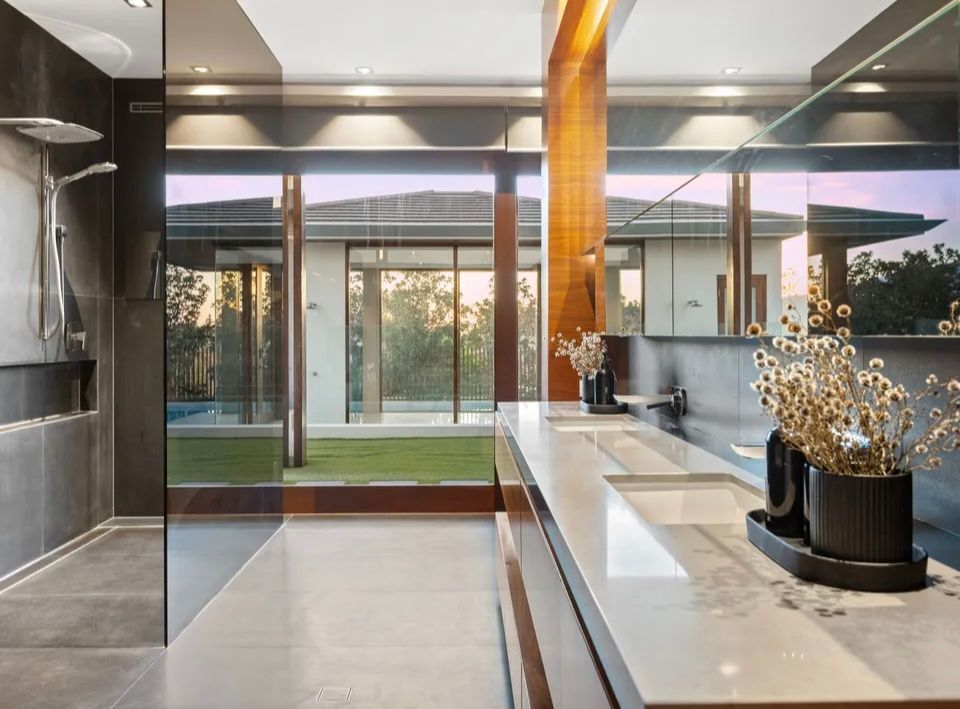 A bathroom with two sinks , a shower and a large window.