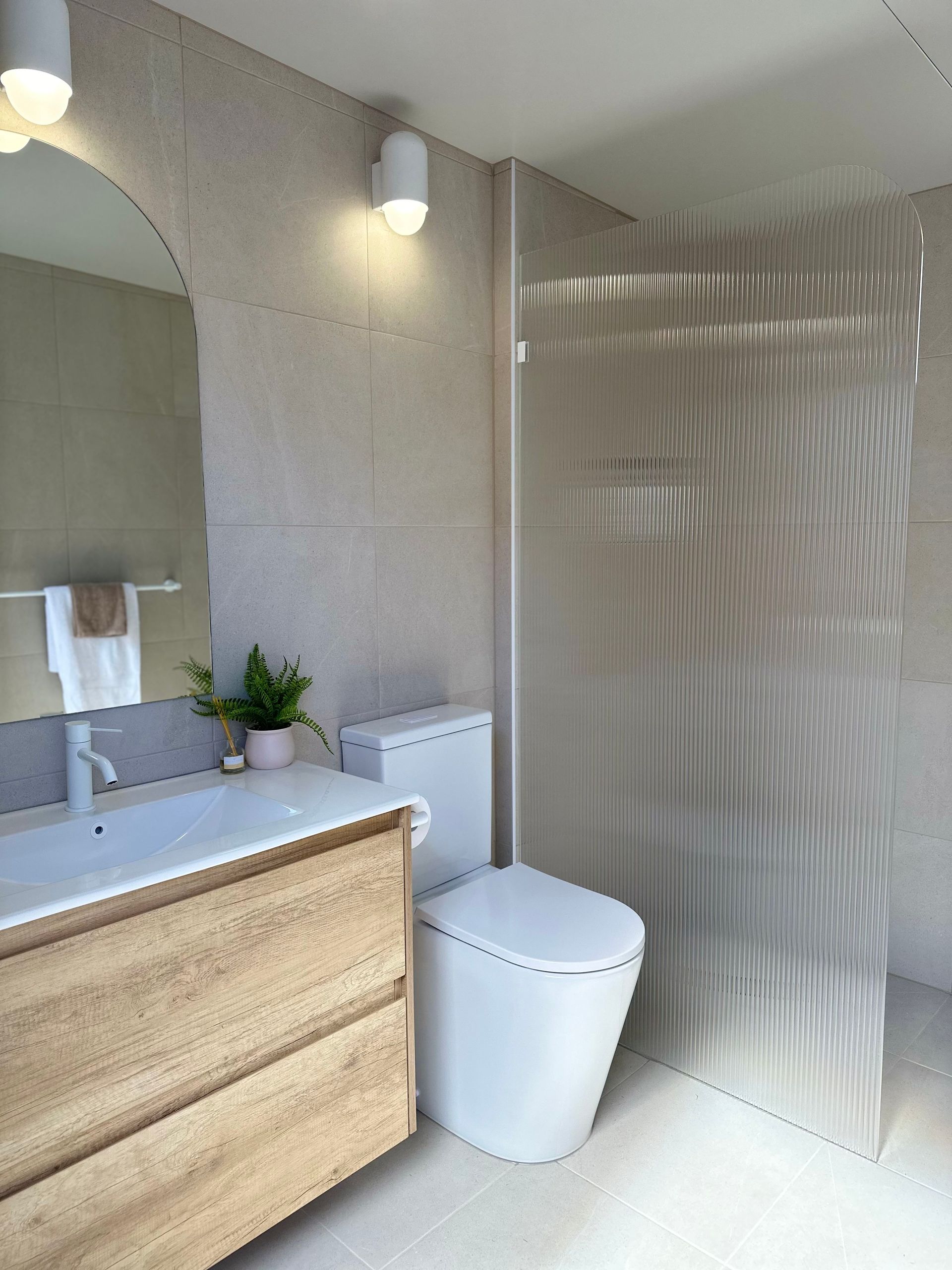 A bathroom with a toilet , sink and mirror