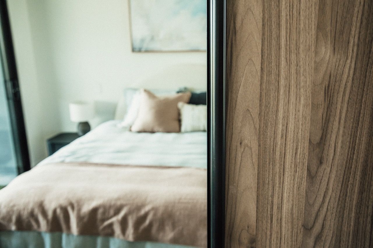 A bedroom with a bed and a closet with sliding glass doors.