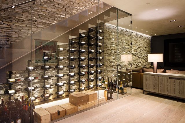A glass of wine is sitting on a table in front of a wine cellar.