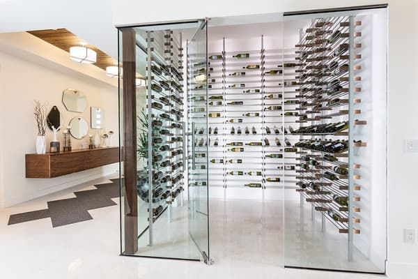 A wine cellar filled with lots of bottles of wine in a living room.