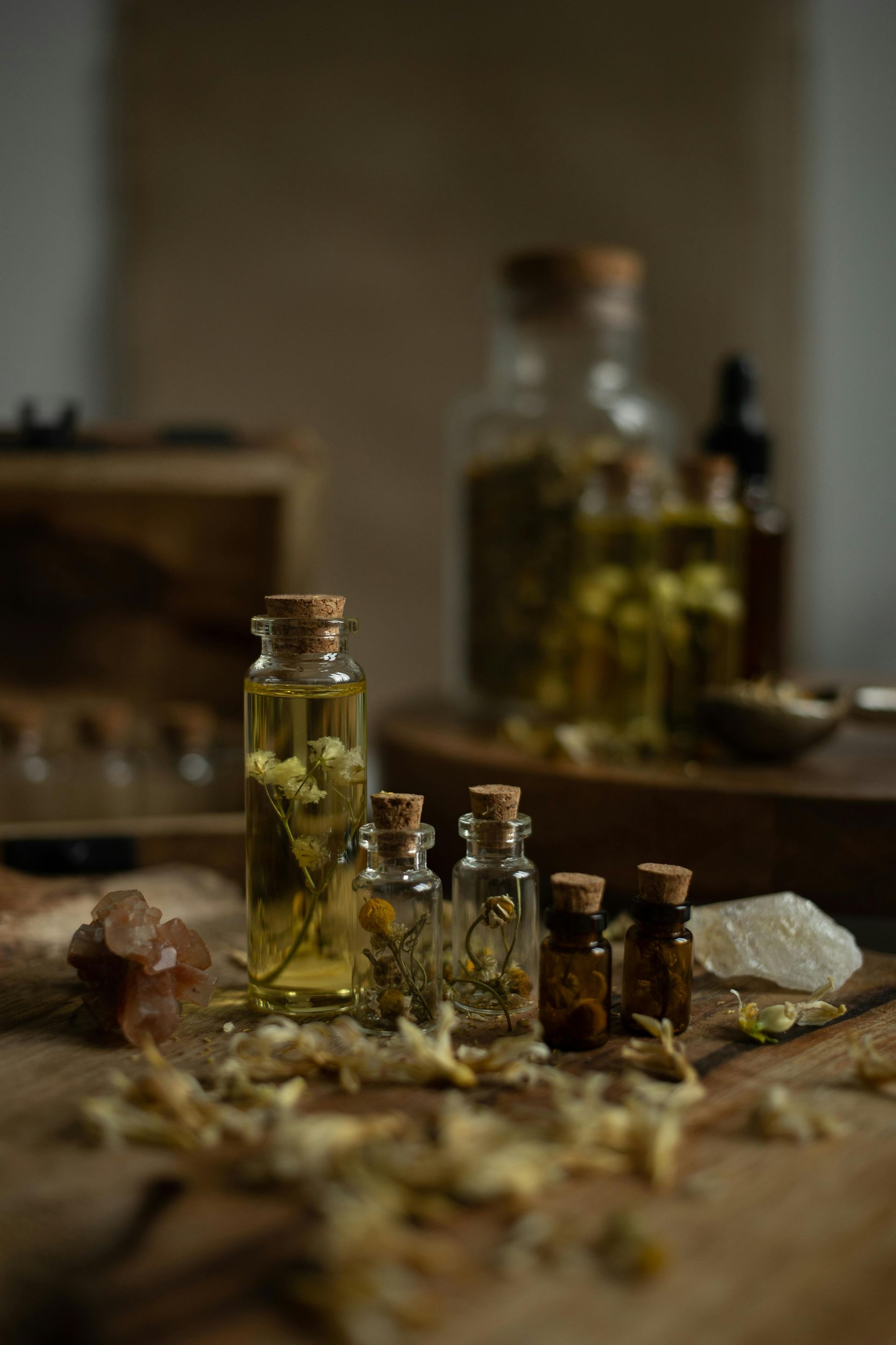Bottles of herbal oil on a wooden surface, with herbs and a clear stone, natural light — All Body Holistic Health in Thuringowa Central, QLD