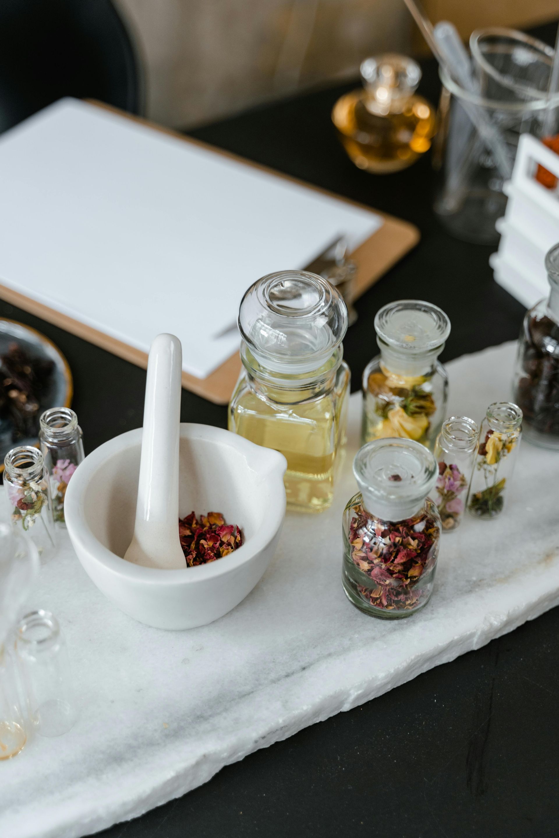 Mortar and pestle with dried herbs, surrounded by glass jars of ingredients on a white cloth — All Body Holistic Health in Thuringowa Central, QLD