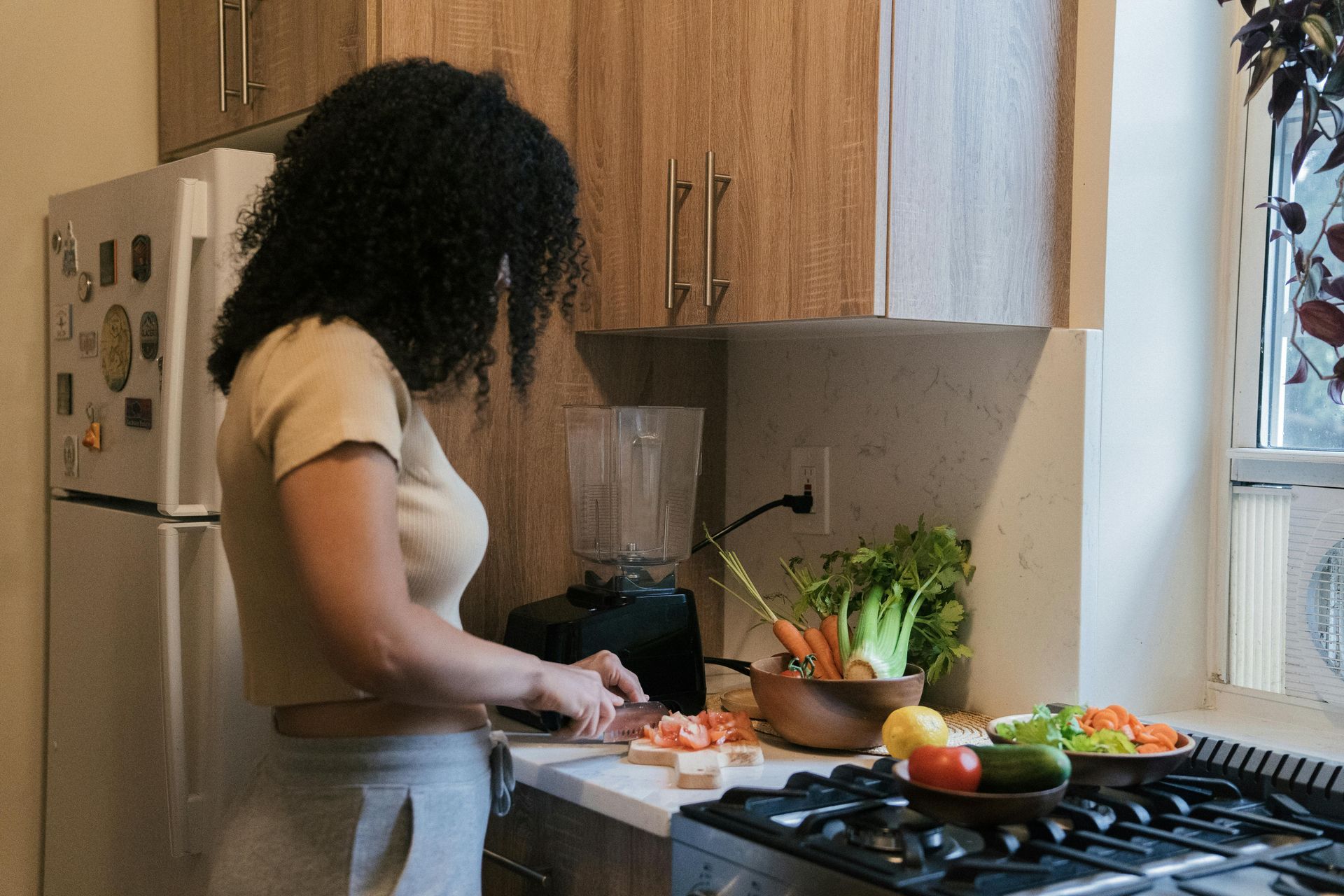 Woman in kitchen cutting vegetables for blending — All Body Holistic Health in Thuringowa Central, QLD