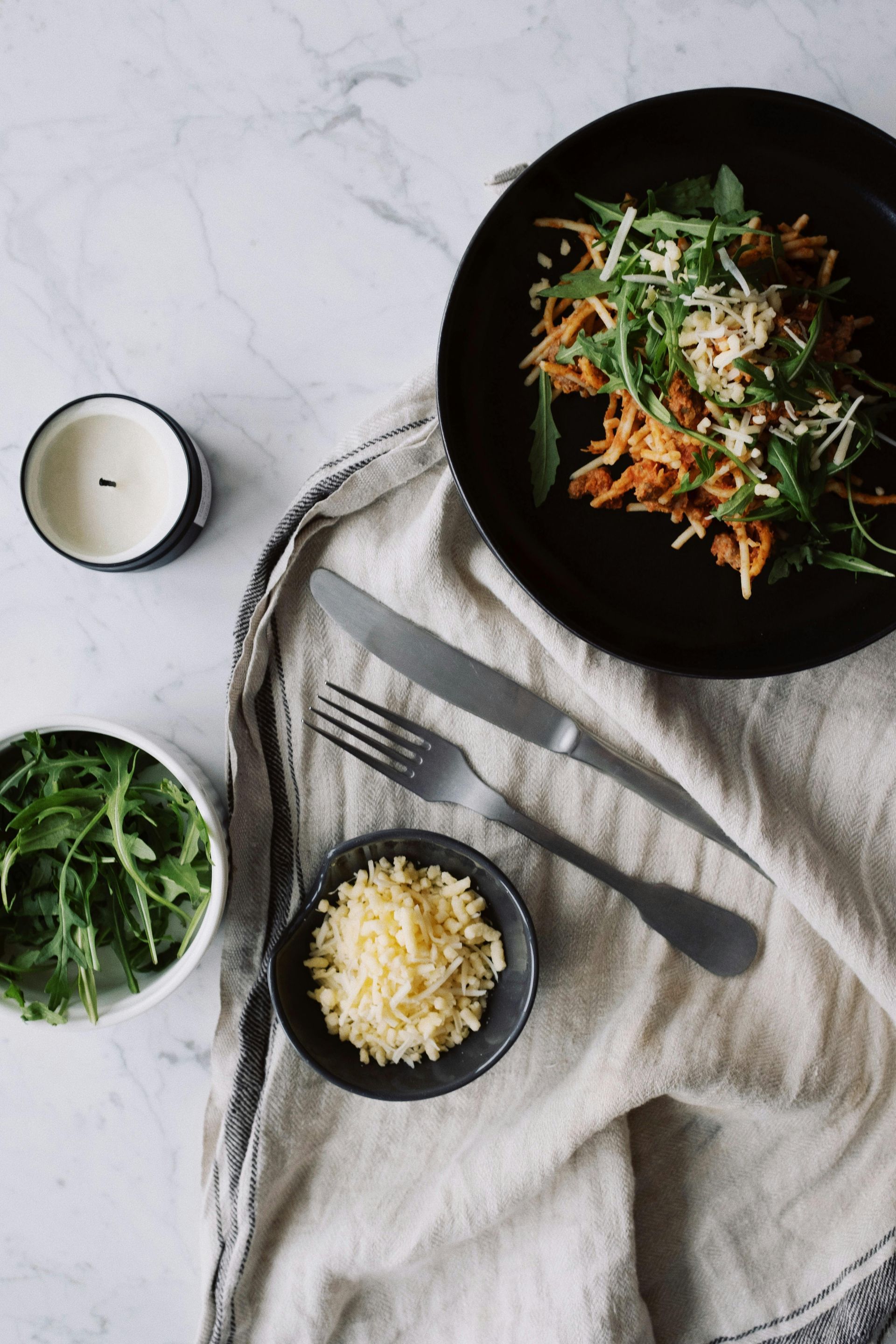 Plate of food with arugula, carrots, and cheese; table setting with candle and utensils — All Body Holistic Health in Thuringowa Central, QLD