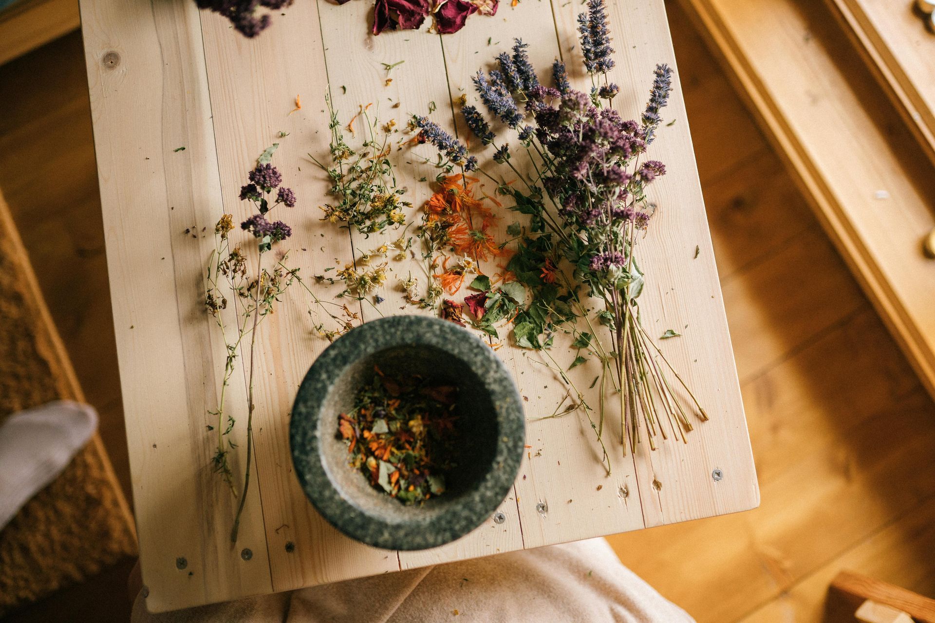 Herbs and flowers on wooden board with mortar and pestle, indoor setting  — All Body Holistic Health in Thuringowa Central, QLD