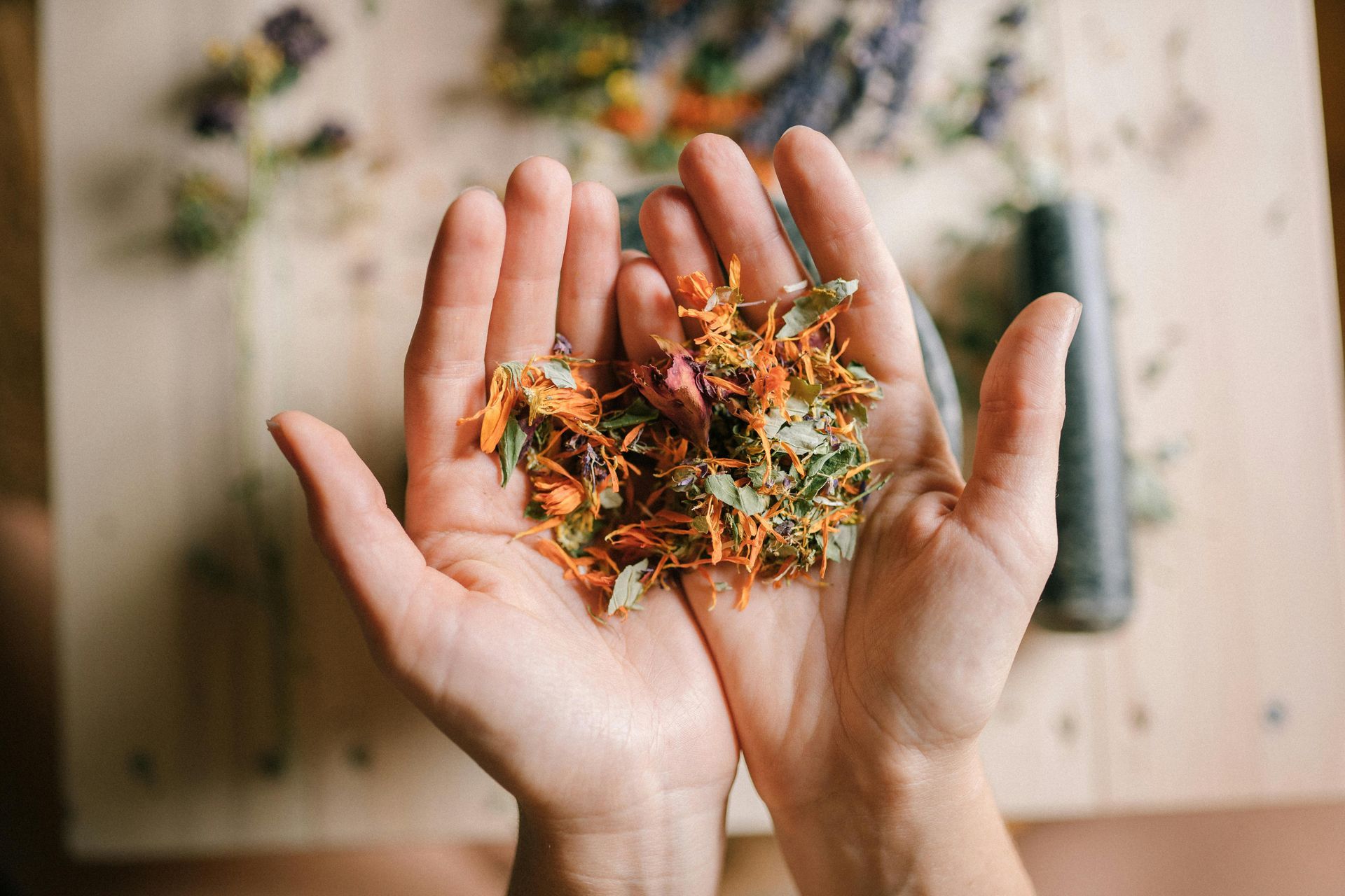 Hands cupped, holding colourful dried herbs and flowers, blurred wooden background — All Body Holistic Health in Thuringowa Central, QLD