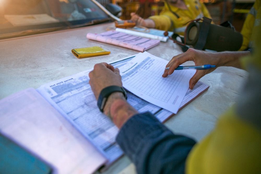 A Person is Sitting at a Table Writing on a Piece of Paper — All Systems Wastewater Maintenance In Jilliby, NSW