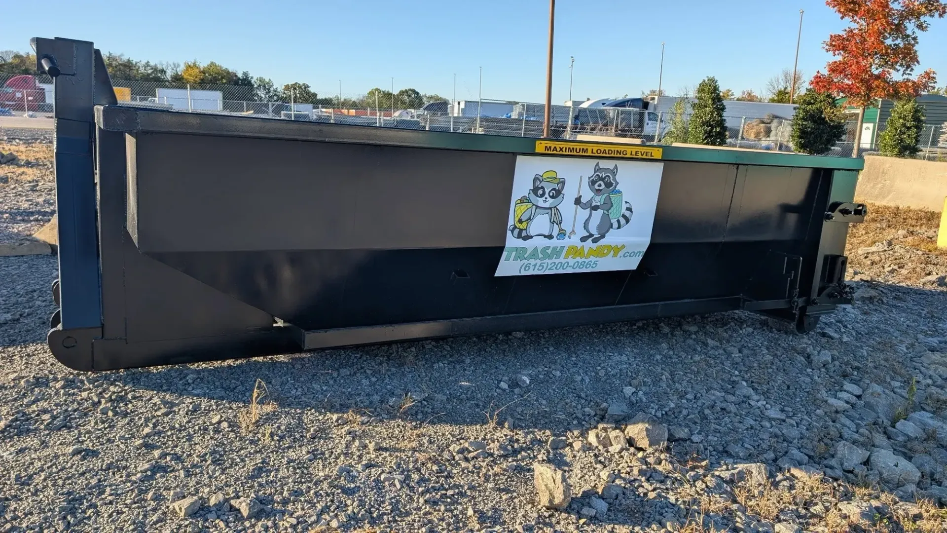 A green dumpster with a yellow trim sits in the snow