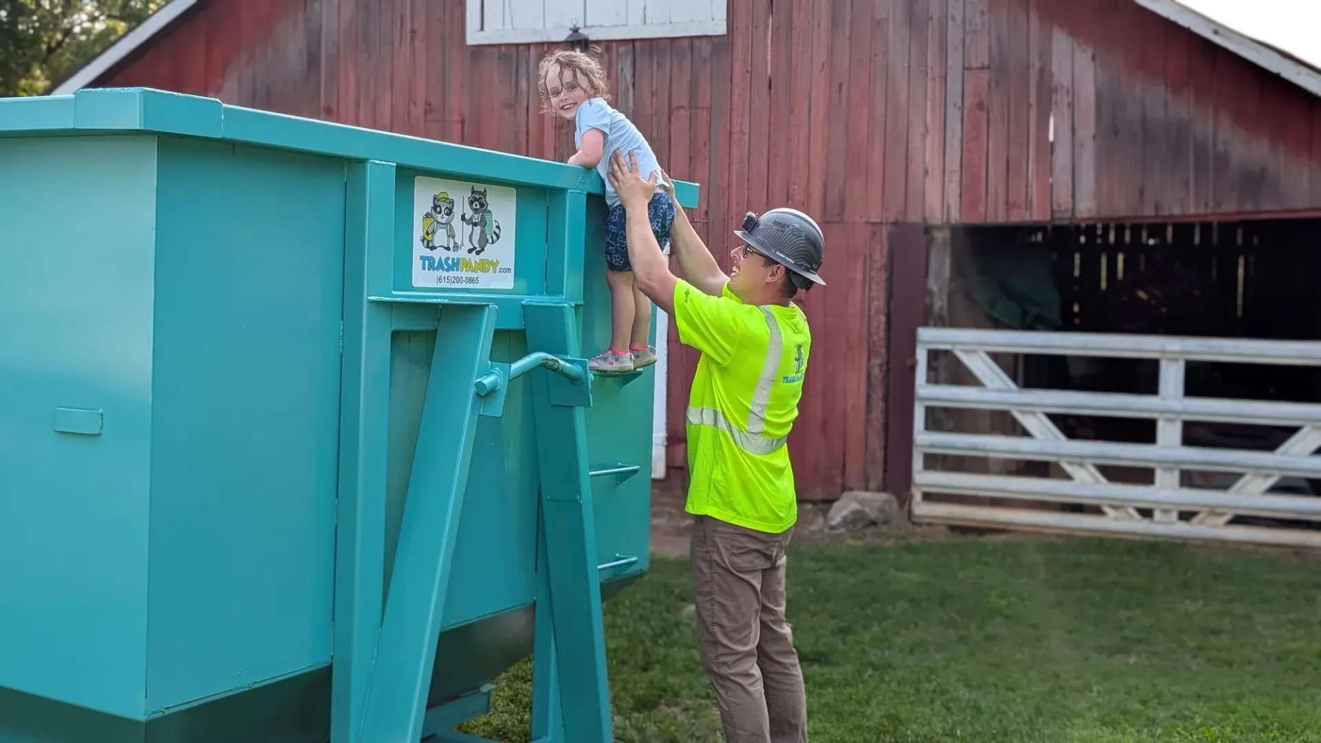 A man is holding a little boy on top of a dumpster.