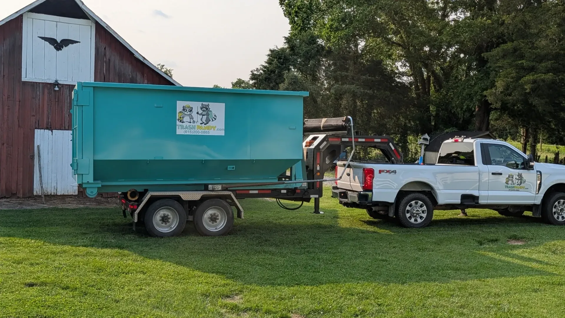 A dump truck with a green dumpster attached to it is parked in a parking lot.