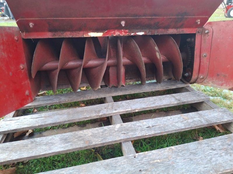 Red snow blower auger, open door, on a wooden pallet.