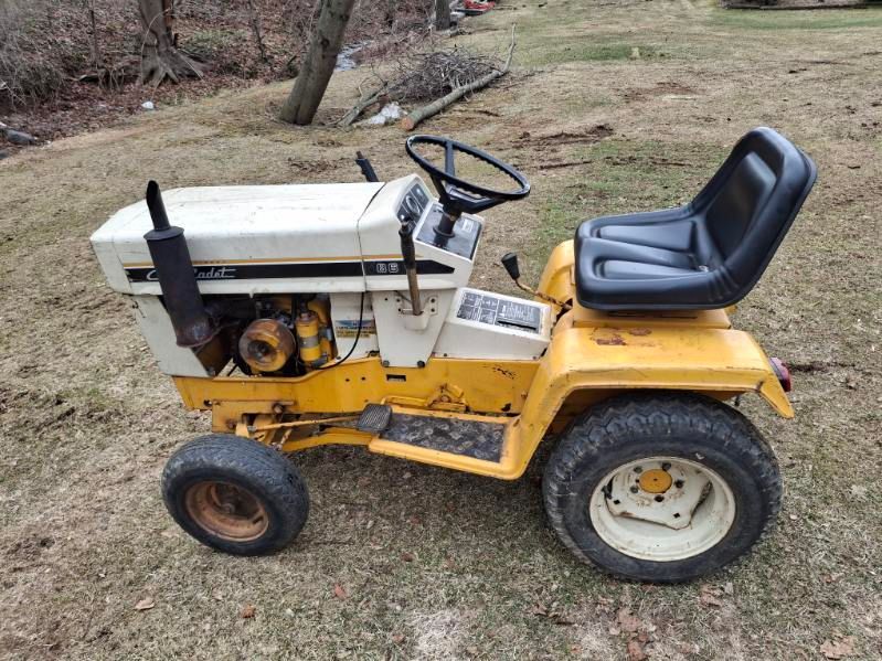 Yellow and white Cub Cadet lawn tractor on grass, with black seat and tires.