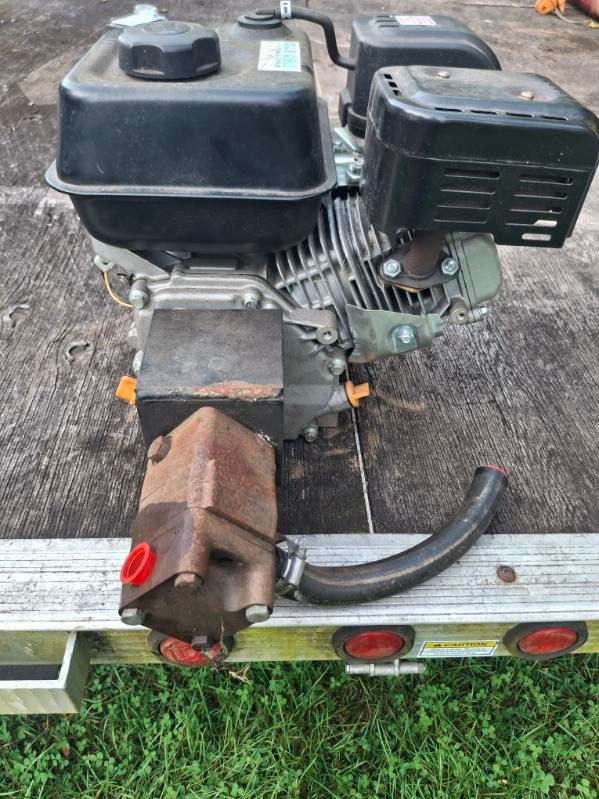 Gas engine with black components and a rusty exhaust on a trailer.