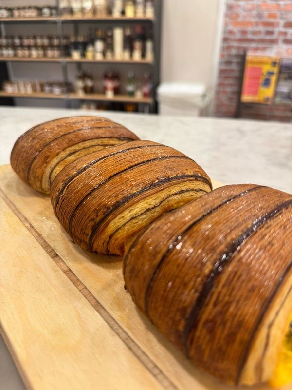 Due pagnotte di pane rustico su un tagliere di legno in una vetrina di una panetteria.