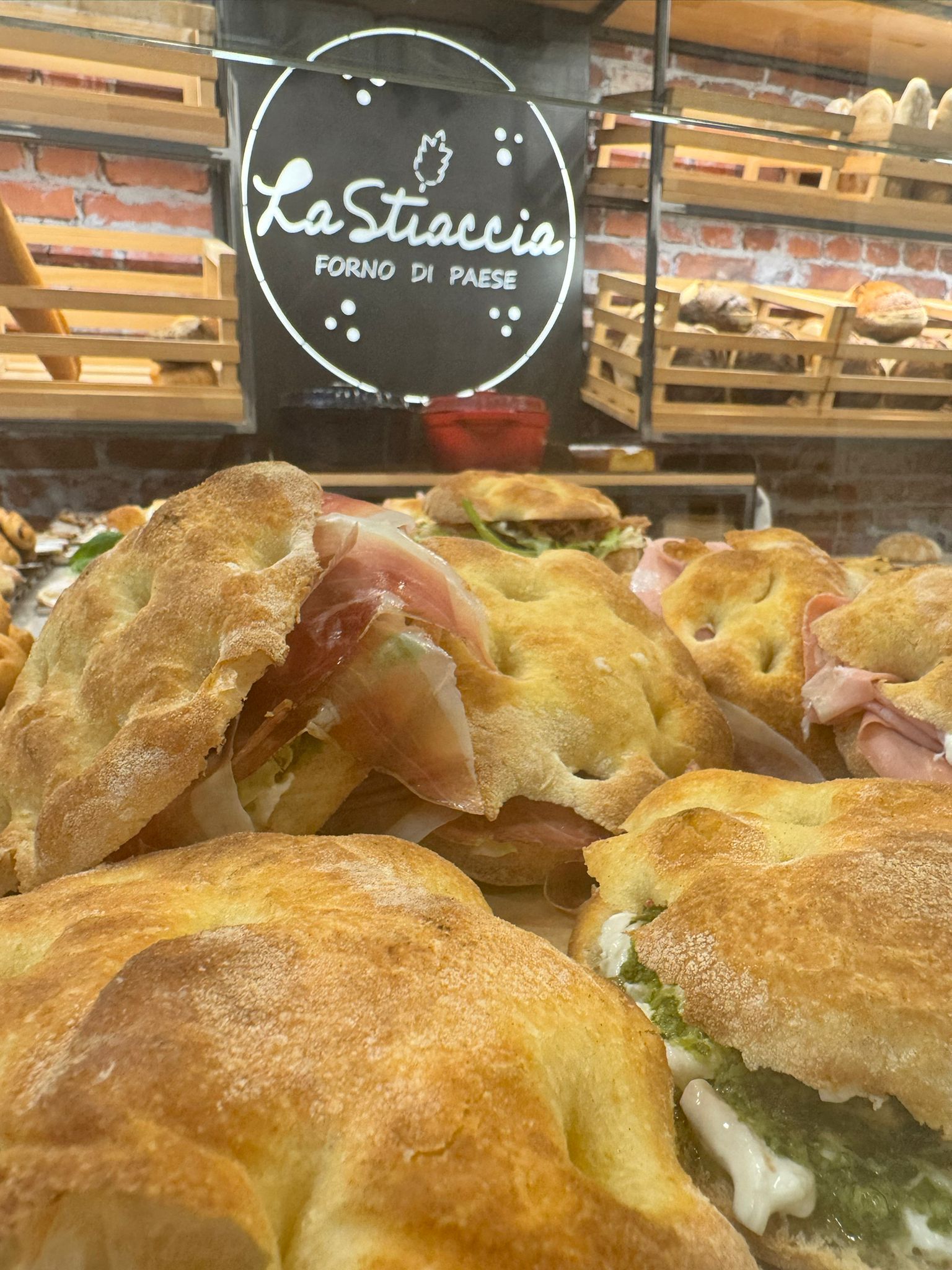 Primo piano di pasticcini ripieni dorati esposti in una vetrina di una pasticceria, con l'insegna 