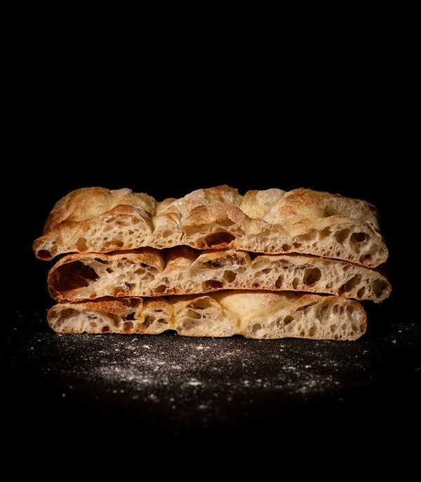 Piadine rustiche impilate su uno sfondo nero, spolverate di farina