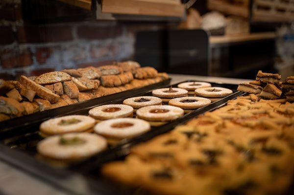 Vassoio di ciambelle e pasticcini assortiti esposti in una vetrina da pasticceria.