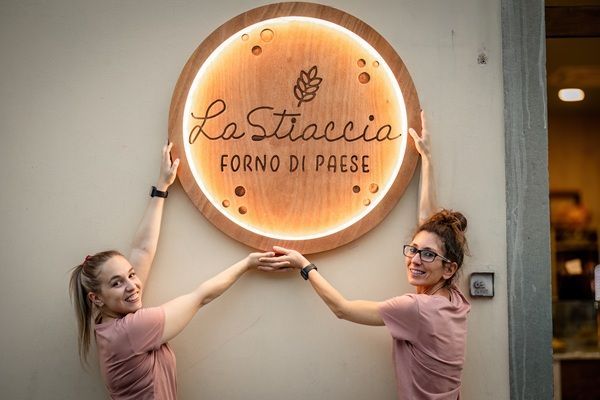 Due donne reggono un'insegna rotonda illuminata con la scritta 
