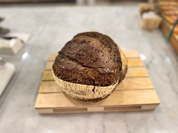 Pagnotta rotonda di pane rustico su un tagliere di legno sul bancone della cucina.
