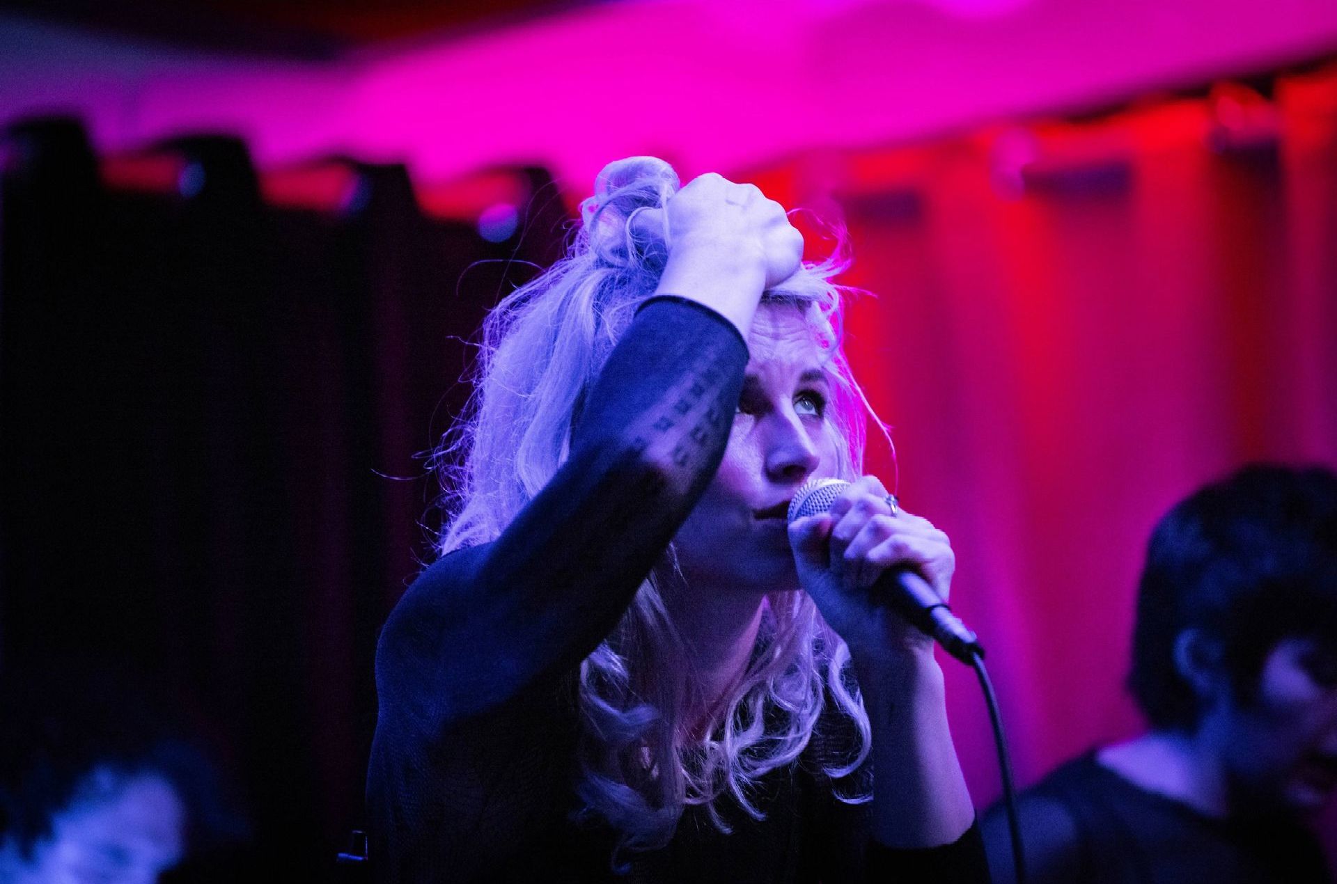 A woman is singing into a microphone in a dark room.